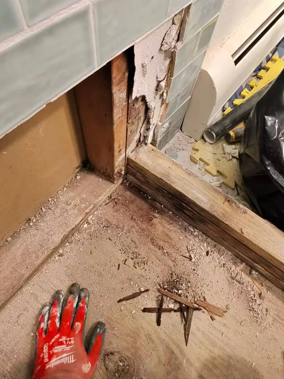 A Denver shower repair exposes the subfloor beneath partially removed gray wall tile.