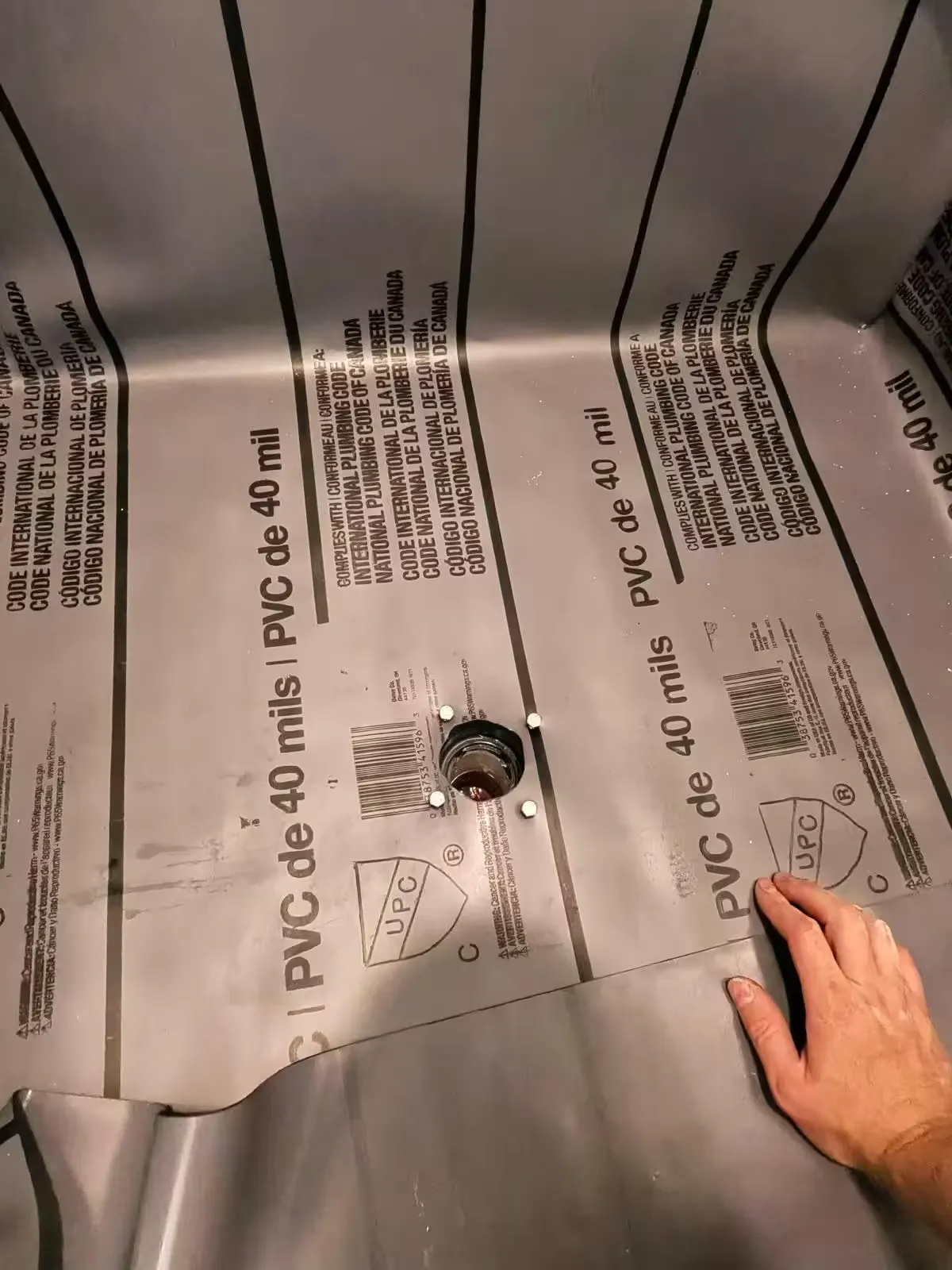 A gray PVC shower liner fits around a central drain in a Denver shower repair.