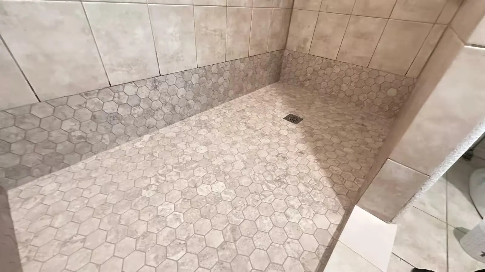 A wide view of an Elizabeth shower after remodeling shows a hexagon-tile floor and a matching band along the lower walls.