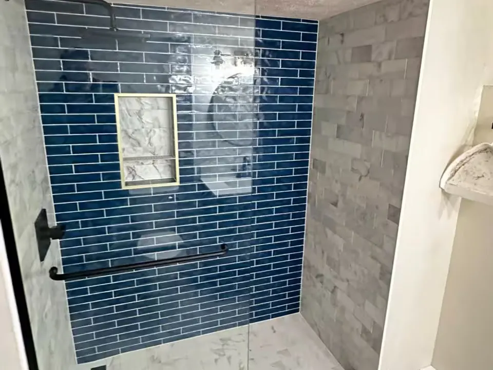 An Aurora basement shower after remodeling has blue rectangular wall tile, a recessed niche, and a glass enclosure.