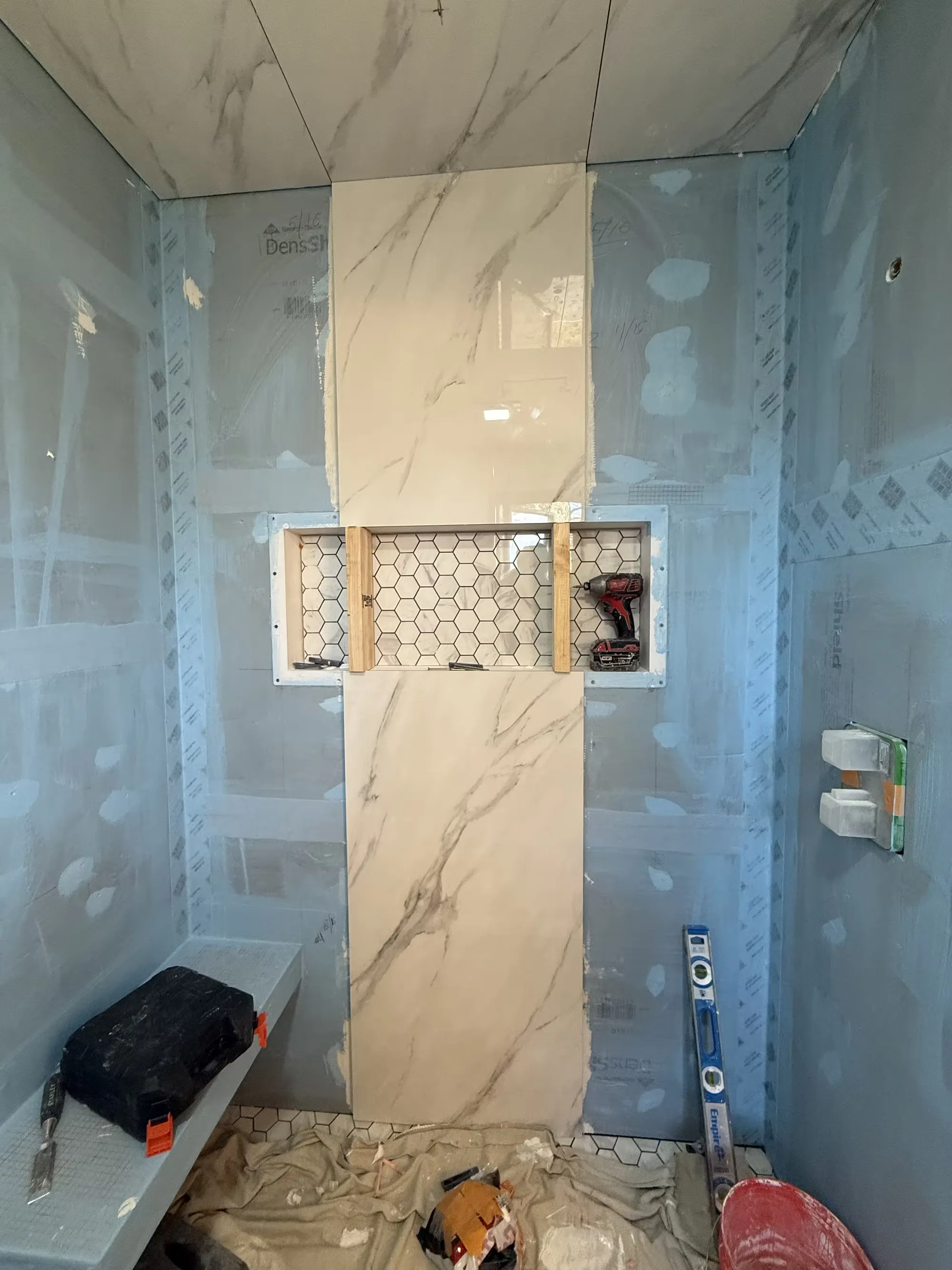 A Littleton shower during preparation has blue wall boards, a partially tiled wall, and a recessed niche.