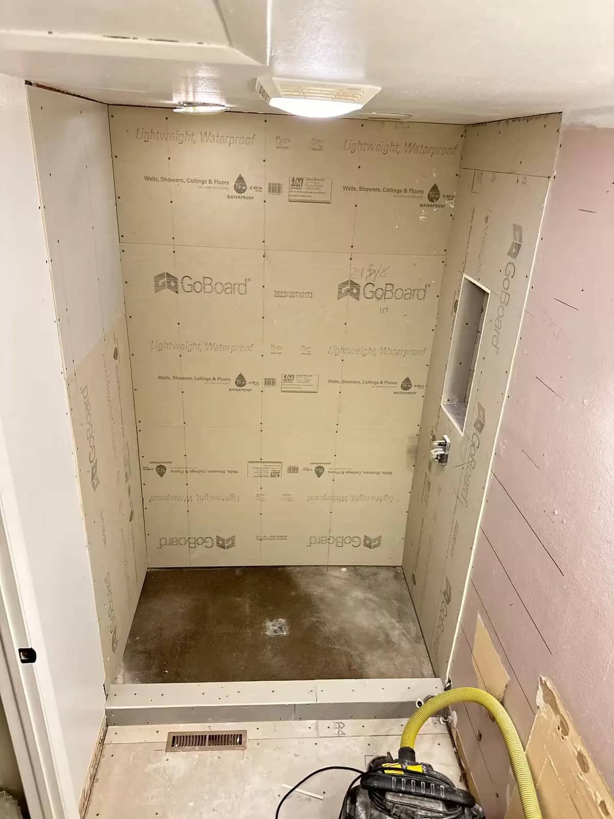 Light-colored wall boards and a recessed niche are visible in an Aurora shower during remodeling.