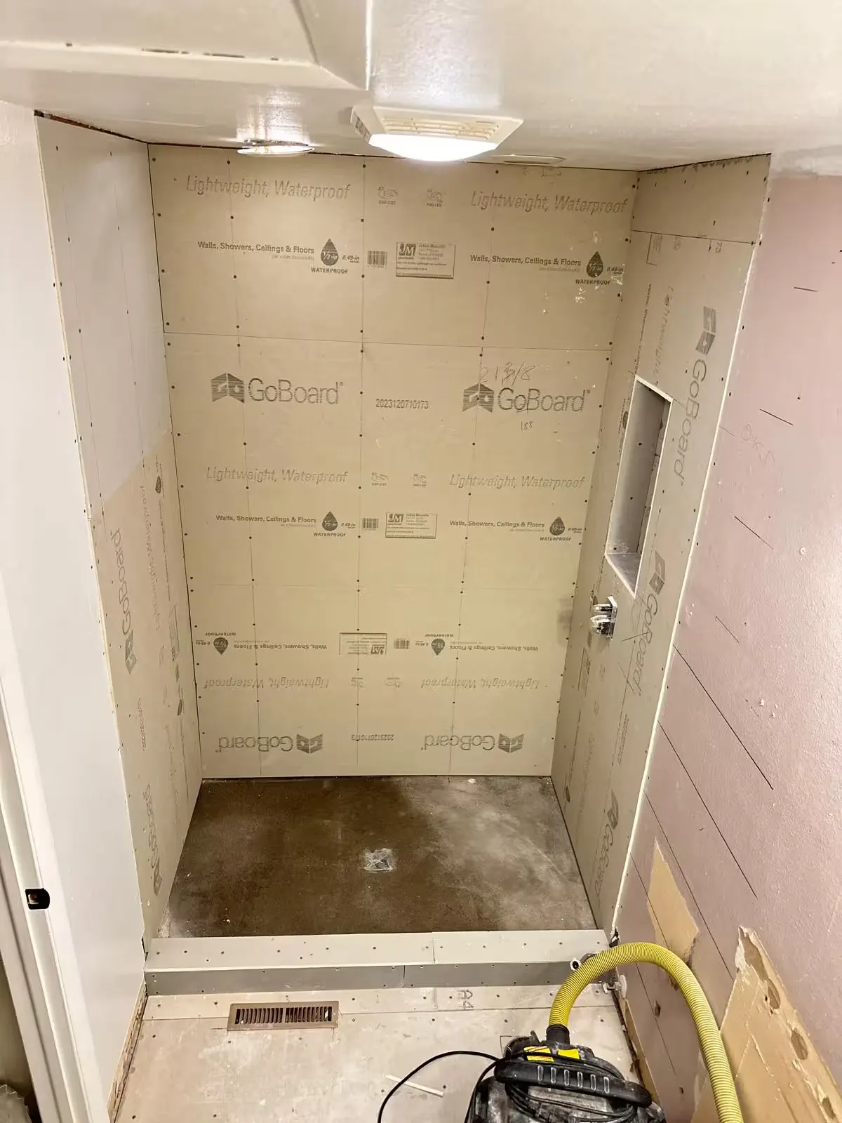 Light-colored wall boards and a recessed niche are visible in an Aurora shower during remodeling.