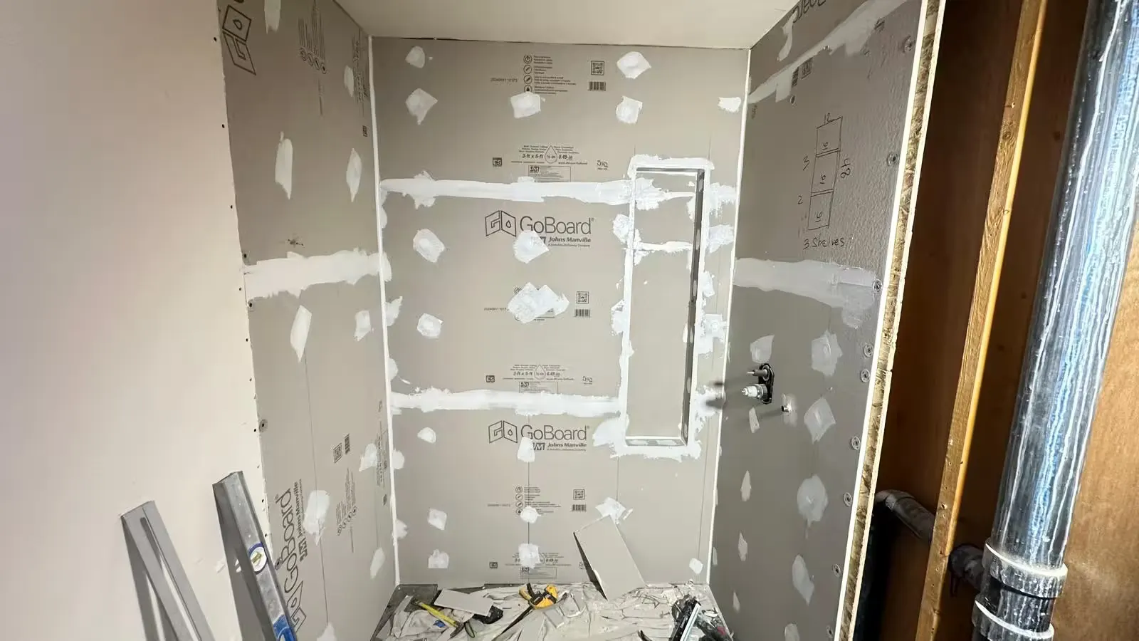 Gray waterproof wall boards with sealed joints surround a tall recessed niche during an Arvada shower remodel.